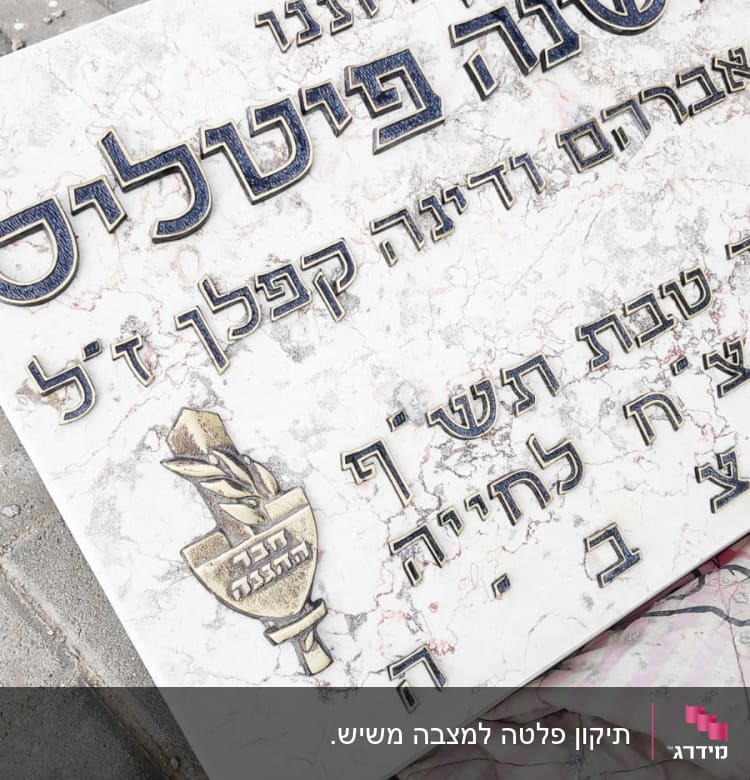 מצבה עם כיתוב בעברית על רקע אבן